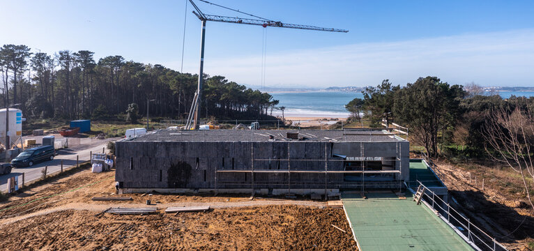 Stone-clad coastal building under construction near beach