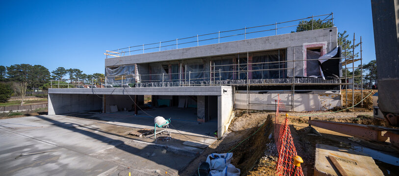 Contemporary stone residence under construction with concrete frame