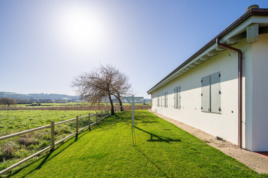 Rural house with garden lawn beside sunlit farmland