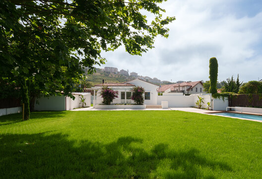 White house with pool and lush garden lawn