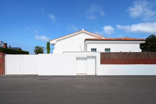 White suburban house with tiled roof behind garden wall
