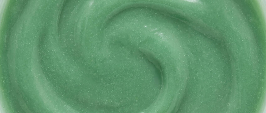 Green cosmetic cream texture background. Swirled medicated ointment or skincare clay mask close up