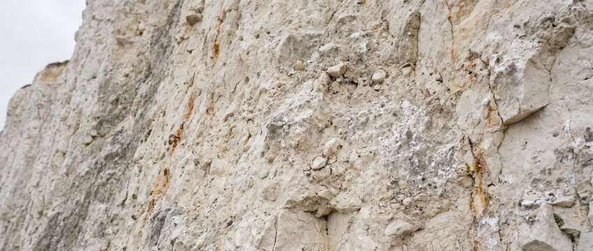 White chalk cliff rock face showing coastal erosion. Detailed view of geological limestone formation