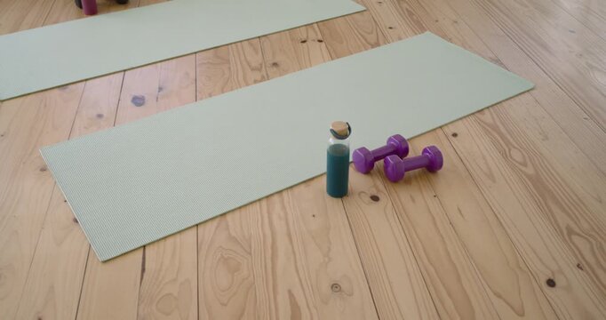 Camera is pulling back and panning left revealing mat bottles weights for living room workout setup