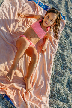 Active smiling Child Lying on a Beach Towel on Pebble Beach