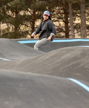 Woman ride bicycle pump track in outdoor skate park
