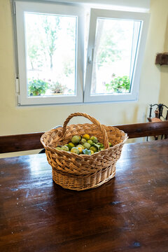 Basket of fresh fruit on wooden table by window