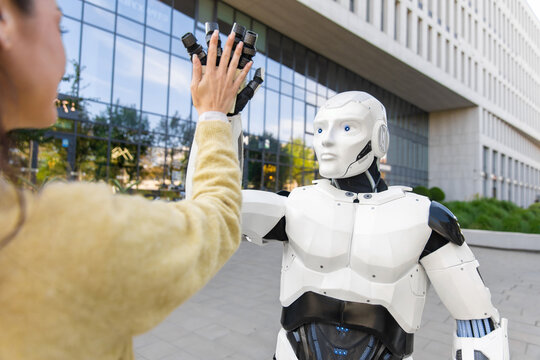 White cybernetic robot giving high five to female partner