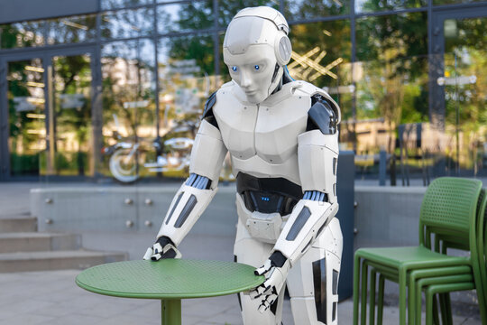 White robotic waiter arranging green round table