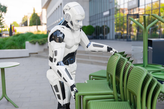 Humanoid robot stacking green chairs