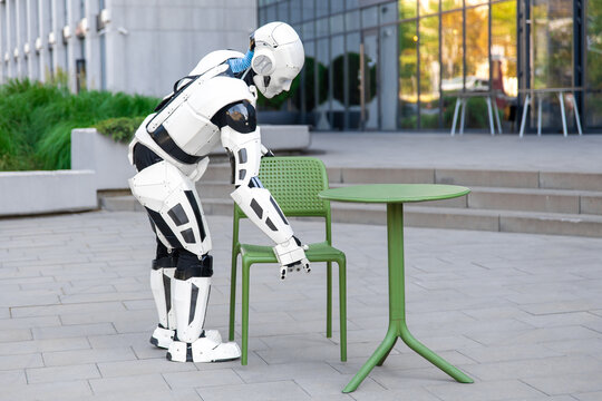 Side view robotic waiter placing chair near table