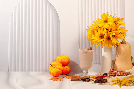 Warming pumpkin latte with cinnamon and star anise, pumpkin and fallen leavesSeasonal abstract composition with hot autumn drink and rudbeckia flowers, , banner for screen, autumn greeting concept.