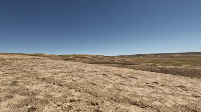 Forward tracking shot over dry cracked badlands earth