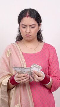 Vertical Shot of Confused Married Indian Woman Counting Cash Indian Rupee (INR) Notes at Home