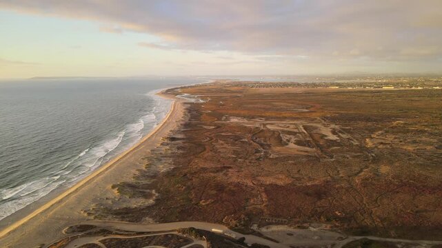 Aerial drone view of US Mexico border wall extending into Pacific Ocean between Tijuana and San Diego