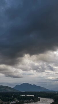 Dramatic Clouds Sweep Across Chilliwack's Fraser Valley with Mountains and River Below in British Columbia