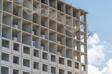 Construction of a modern building unfolds against a bright blue sky showcasing the intricate details of the structure and workers on-site © beholdereye