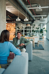 Fototapeta premium Coworkers meeting in a modern office space, man listening and smiling during a professional business discussion