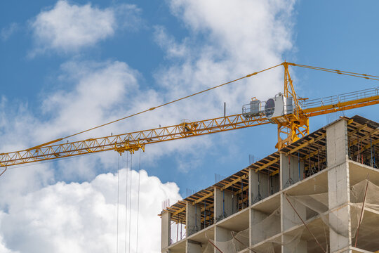 Construction crane towers over a building under progress in a bright blue sky