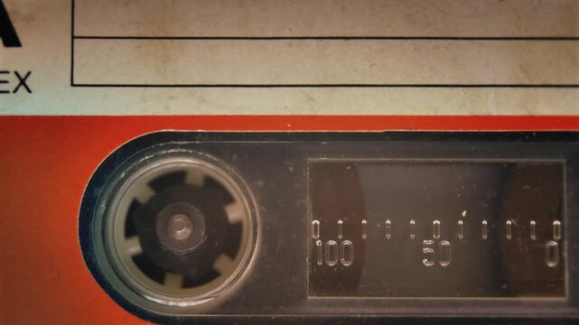 Cassette tape roller, detail macro shot. Dramatic close up video loop of a plastic audio cassette tape, playing