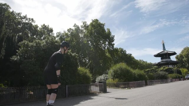 A skater speeds up in Battersea Park, London on a sunny autumn day with his rollerblades next to the thames river