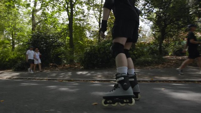 A skater speeds up in Battersea Park, London on a sunny autumn day with his rollerblades 