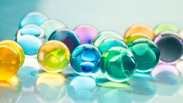 Colorful translucent glass marbles on reflective surface