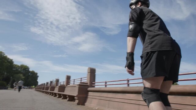 A skater speeds up in Battersea Park, London on a sunny autumn day with his rollerblades 