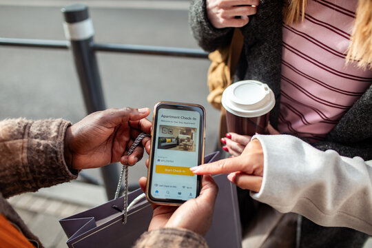 Travelers using smartphone to check in to rental apartment on city street