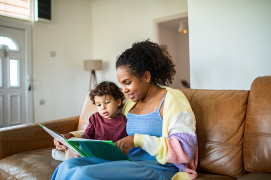 Parent reading storybook with toddler on sofa at home