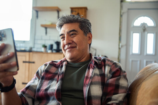 Smiling middle-aged man using smartphone at home