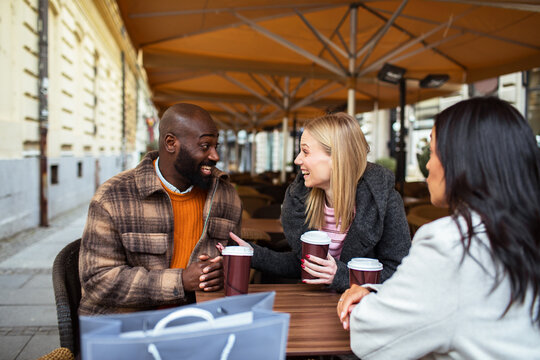 Friends laughing over coffee at outdoor city cafe