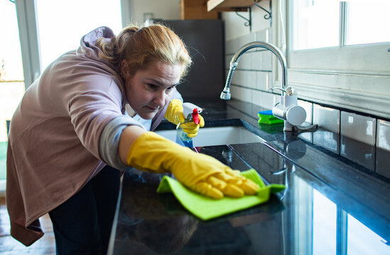 Woman cleaning kitchen countertop at home