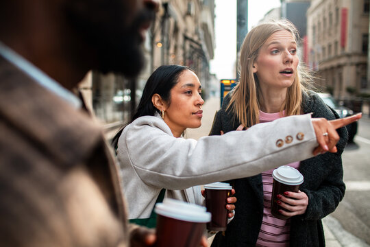 Friends with takeaway coffee navigate city street