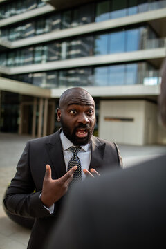 Businessman reacting in heated discussion outside modern office building