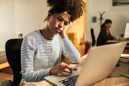Worried young woman working on laptop at office desk