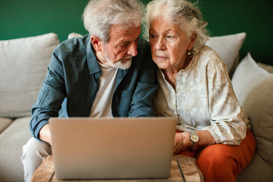 Concerned senior couple using laptop at home
