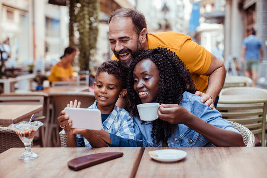 Family watching smartphone together at outdoor cafe