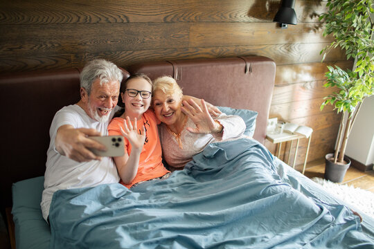 Grandparents and grandchild taking selfie in bed at home