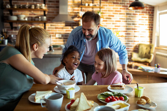 Parents and children enjoying breakfast in home kitchen