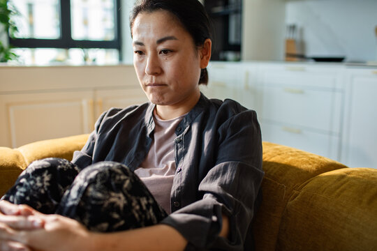 Worried woman sitting on sofa at home