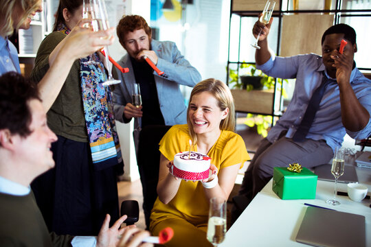 Coworkers celebrating birthday with cake in office