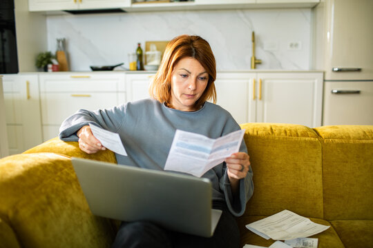 Woman reviewing bills on laptop at home
