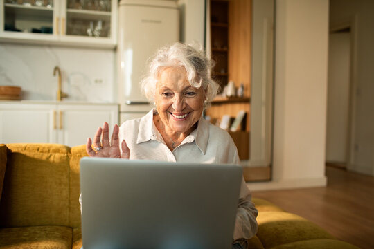 Smiling senior woman video calling on laptop at home