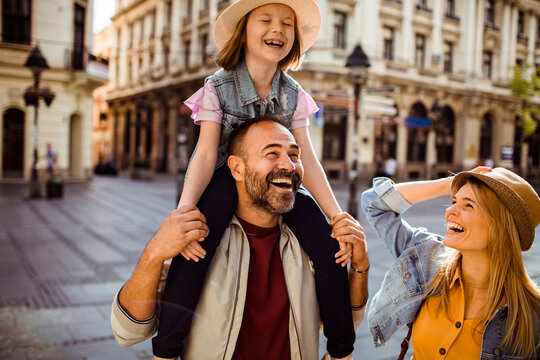 Parents with daughter laughing on city street