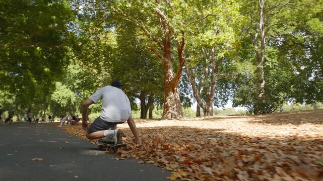 A skateboarder is having fun on his skate in Battersea Park, London on a sunny autumn day