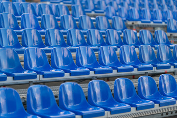 Rows of vibrant blue seats await eager spectators at a lively sports stadium on a bright sunny day