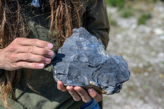 Woman holding large flint rock specimen during field study.