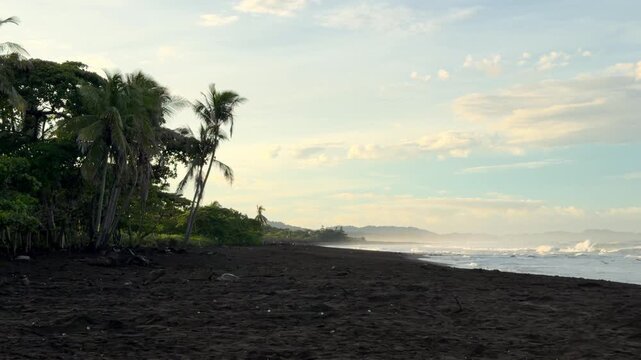 Tropical black sand beach with ocean waves crashing