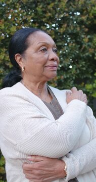 Vertical video: Senior African American woman smiling then laughing after offscreen cue by hedge